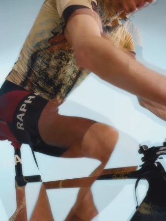 Cyclist in motion wearing a cycling jersey and shorts on bicycle, clear background, indoor setting, motion blur effect, fitness concept.