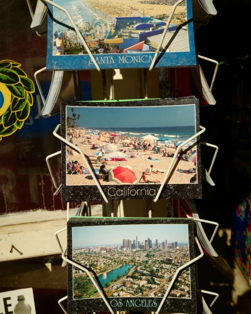 Postcard display featuring beach scene in California, Santa Monica views, and Los Angeles cityscape, sunny outdoor setting.