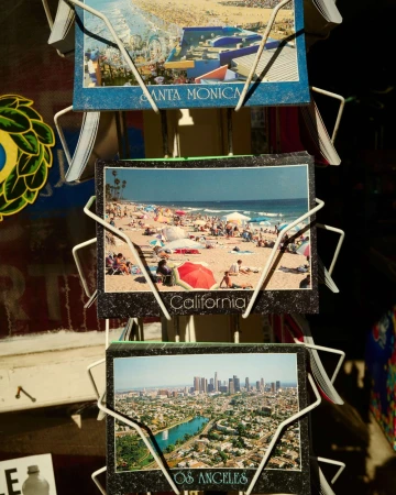 Postcard display featuring beach scene in California, Santa Monica views, and Los Angeles cityscape, sunny outdoor setting.