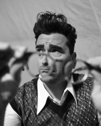 Dan Levy holding glasses up to his face in a monochrome portrait photographed by Brad Torchia