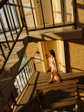 Woman walking along an exterior motel walkway near the ocean, captured by photographer Brad Torchia in Los Angeles.