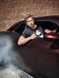 Ryan Gosling sitting in a dark red sports car with smoke rising from the tires against a brick wall backdrop.