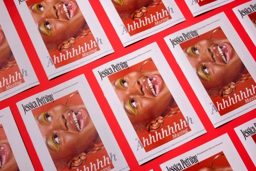 Multiple identical magazine covers featuring a close-up portrait with green eyeshadow and glossy lips on a bright red background.