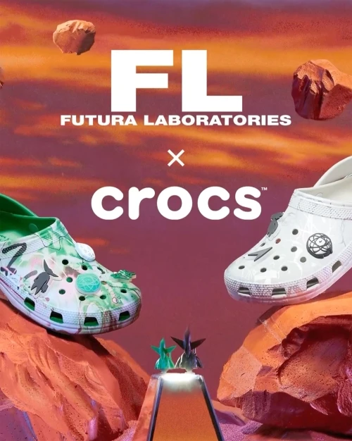 Two Crocs sandals, one green and one white, sit on an orange rock pedestal with a sky-themed background and brand logos visible.