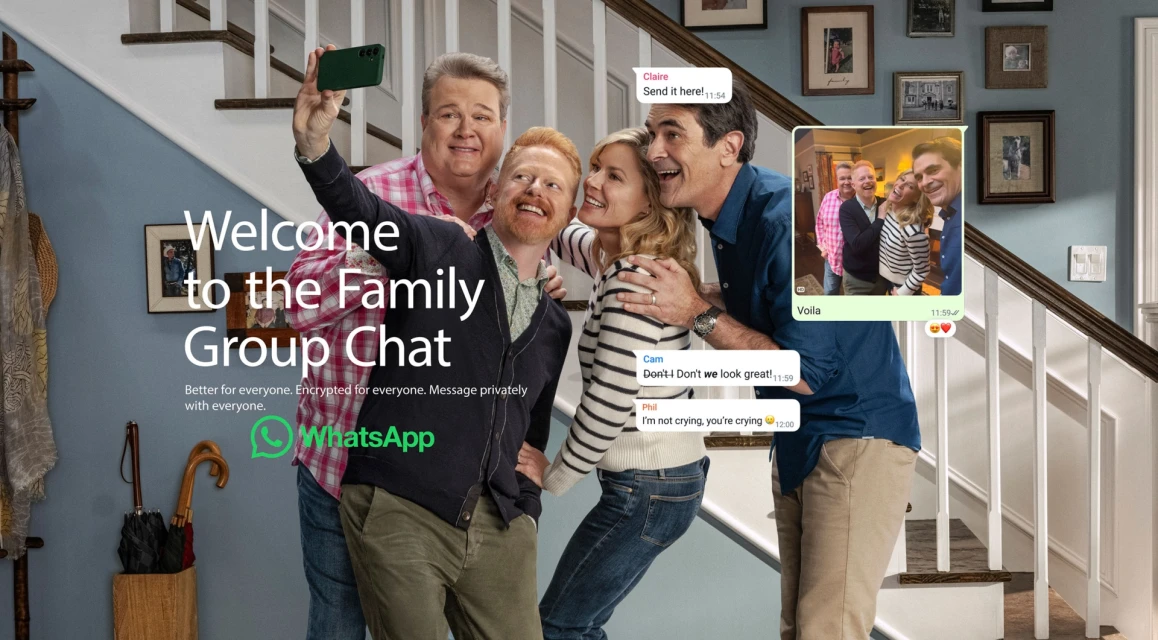 Four adults smile for a selfie in a home interior with stairs and framed photos while a WhatsApp message appears on the right.