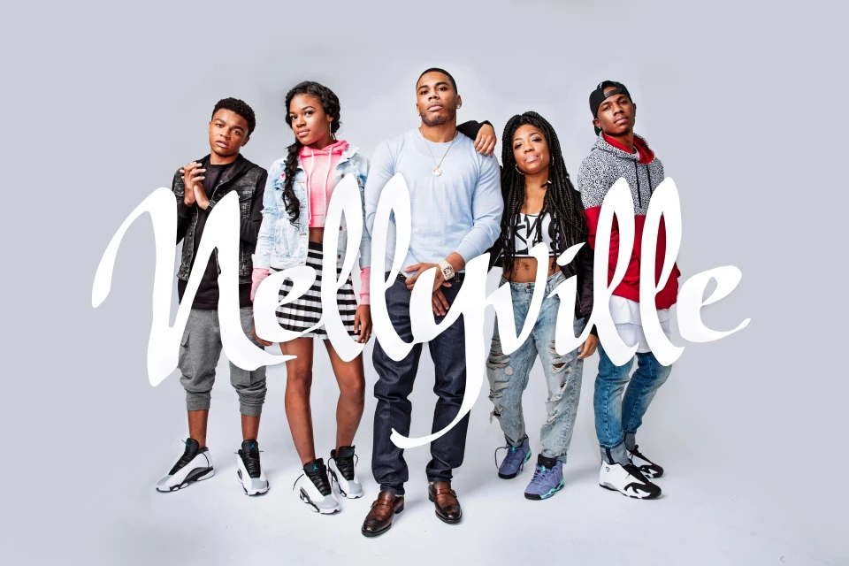 Group portrait of Nelly and four young adults standing indoors against a grey backdrop with the text 'Nellyville' superimposed in white.