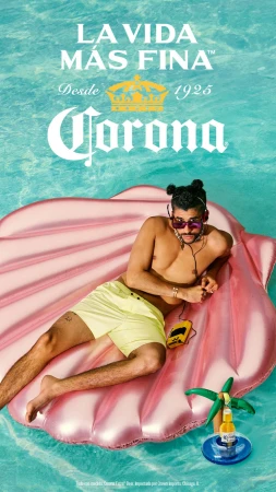 Man relaxes on seashell float in pool with Corona beverage; clear turquoise water, tropical vacation mood, leisure, and vibrant summer scene.