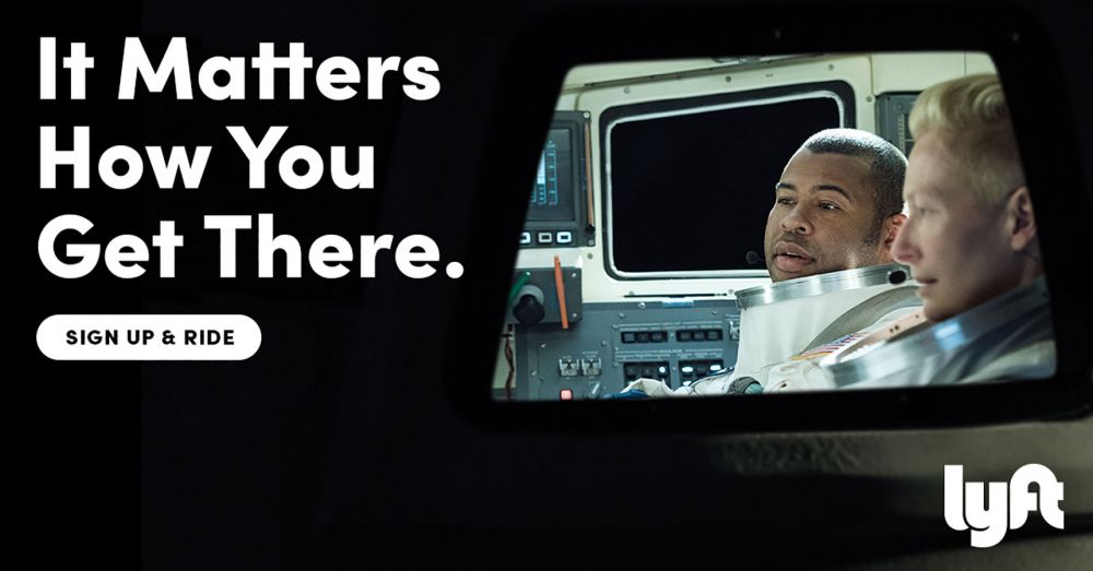 Two astronauts inside a space shuttle cockpit for a Lyft advertisement with text overlay promoting signing up and riding.