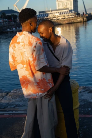 Two black men embracing by the waterfront at sunset, photographed by João Canziani.