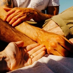 Close-up of hands resting on legs outdoors in bright sunlight, photographed by Jake Stangel in San Francisco.