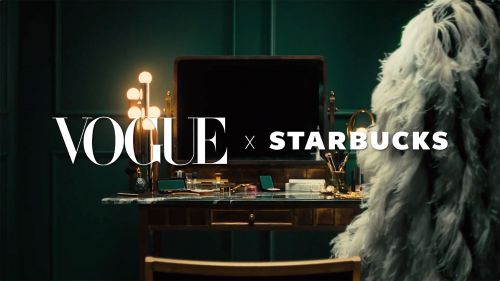 Vanity table setup with cosmetics, illuminated makeup mirror, and white feathered boa. Vogue x Starbucks branding visible in the scene.