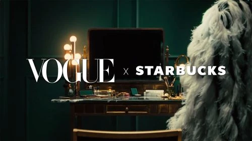 Vanity table setup with cosmetics, illuminated makeup mirror, and white feathered boa. Vogue x Starbucks branding visible in the scene.