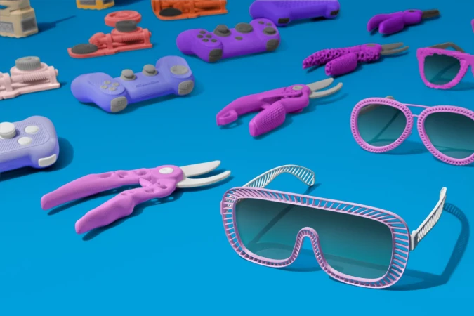 Studio shot of pink and purple toy objects, including game controllers, sunglasses, toy pliers, and toy machines, on a blue background.