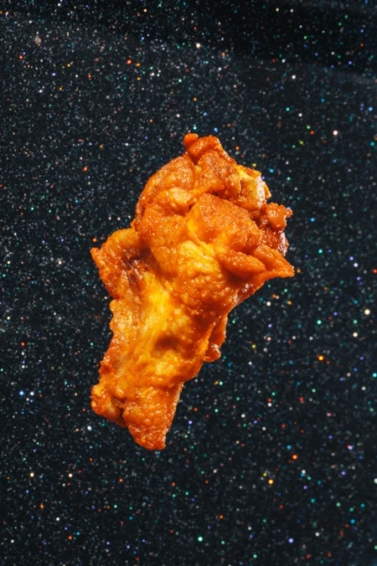 An abstract golden fried food item on a dark blue and black speckled background that resembles a starry night sky.