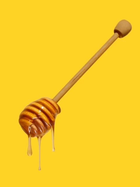 Golden honey drips from a wooden honey dipper against a bright yellow backdrop, highlighting its viscous texture and natural sweetness.