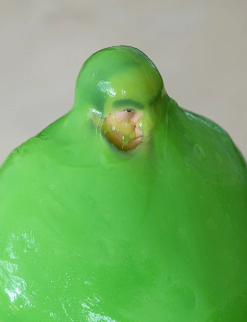Surreal image of a person seemingly encased in a semi-transparent green gel or slime, highlighting the face and head.