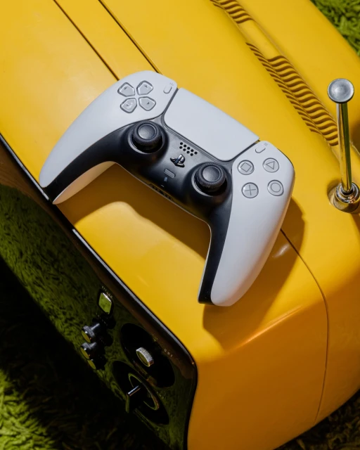 PlayStation 5 DualSense controller resting on a vintage yellow radio, set against a green shag rug background for a retro gaming aesthetic.