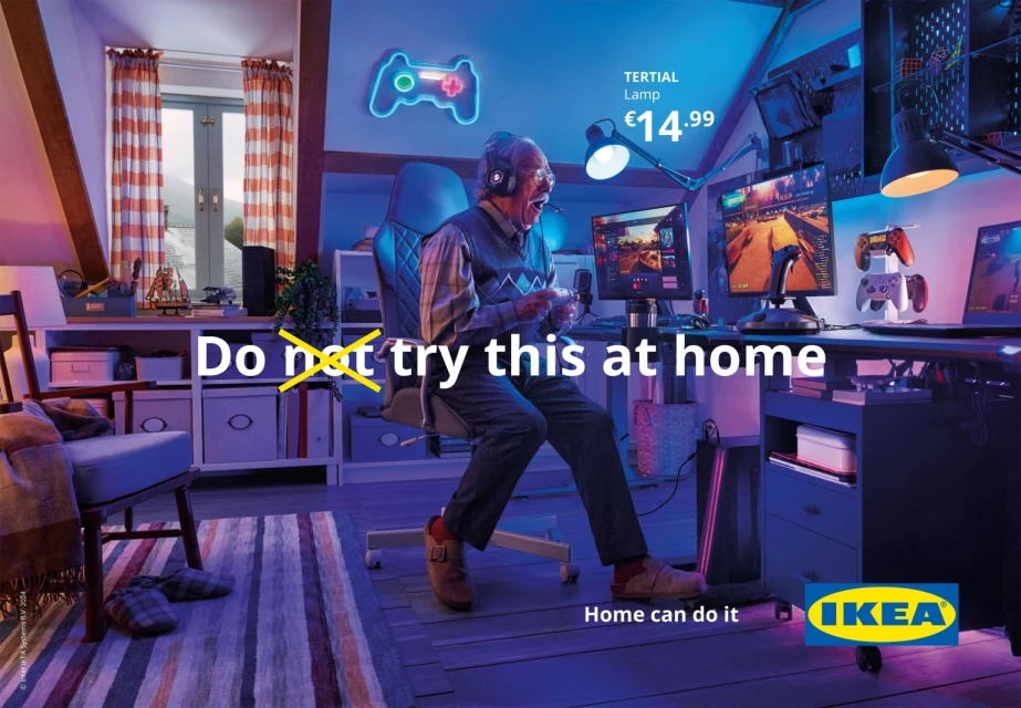 An elderly man with headphones plays video games in a blue-lit room, including dual monitors, gaming chair, and game-themed decor.