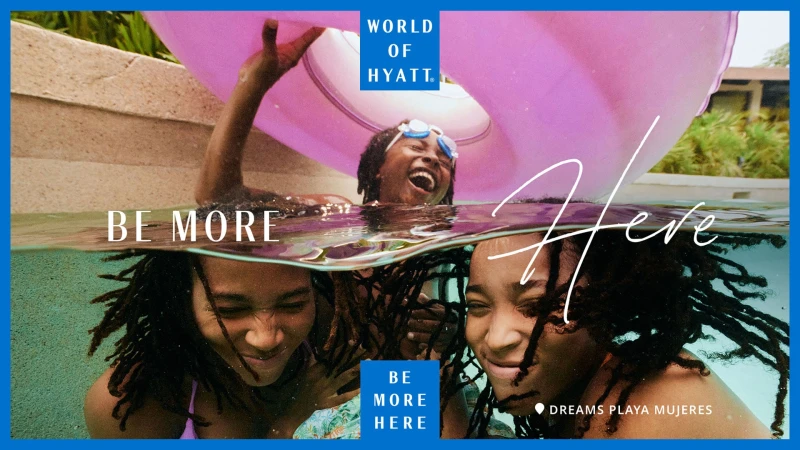 Three women in a swimming pool, with one wearing goggles and holding a pink inflatable ring. Part of the World of Hyatt promotional campaign.
