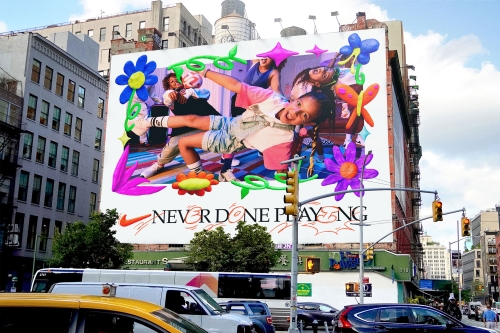 Eye-level view of a Nike billboard in an urban environment featuring an energetic girl and 'Never Done Playing' text. 