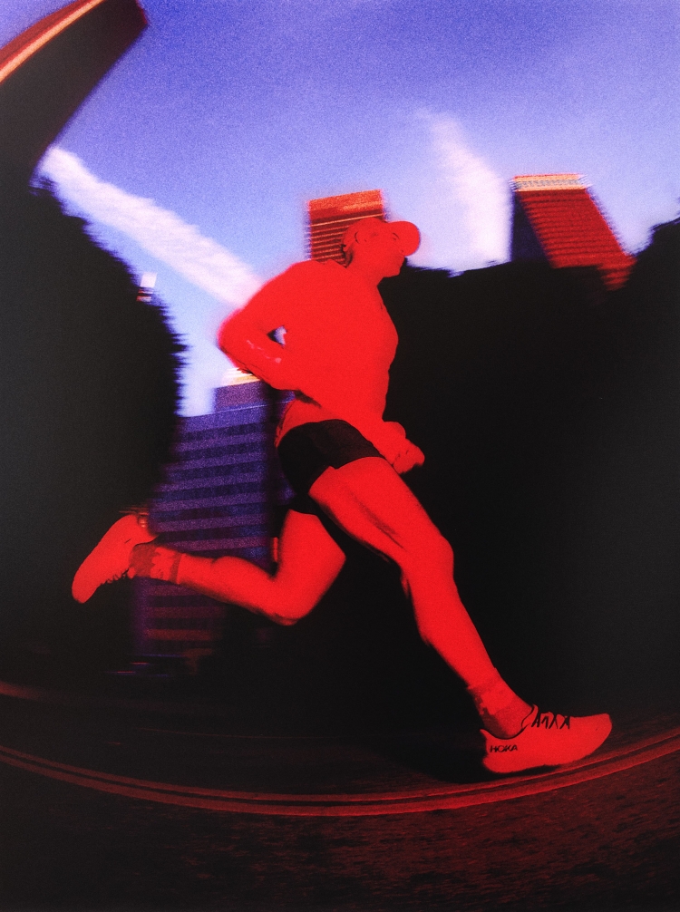 A male runner in motion on a track in an urban setting, rendered in a high-contrast red and blue color palette.