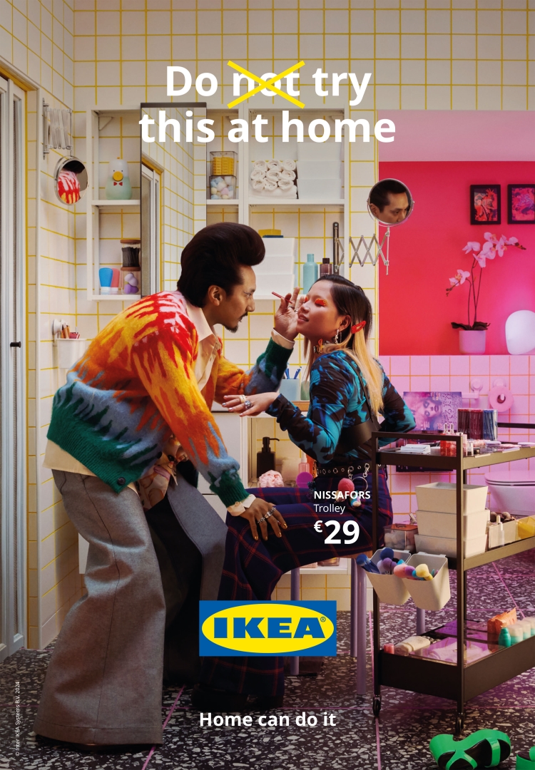 A colorful IKEA ad in a tiled bathroom features a man applying makeup to a woman near a NISSAFORS trolley, alongside a pink orchid.