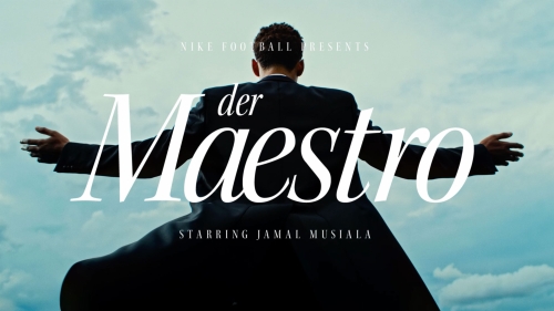 Man in suit with arms outstretched against a cloudy blue sky. Nike football presents Jamal Musiala as der Maestro.