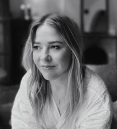 Monochrome portrait of a blond woman wearing a white textured blouse looking thoughtfully off-camera