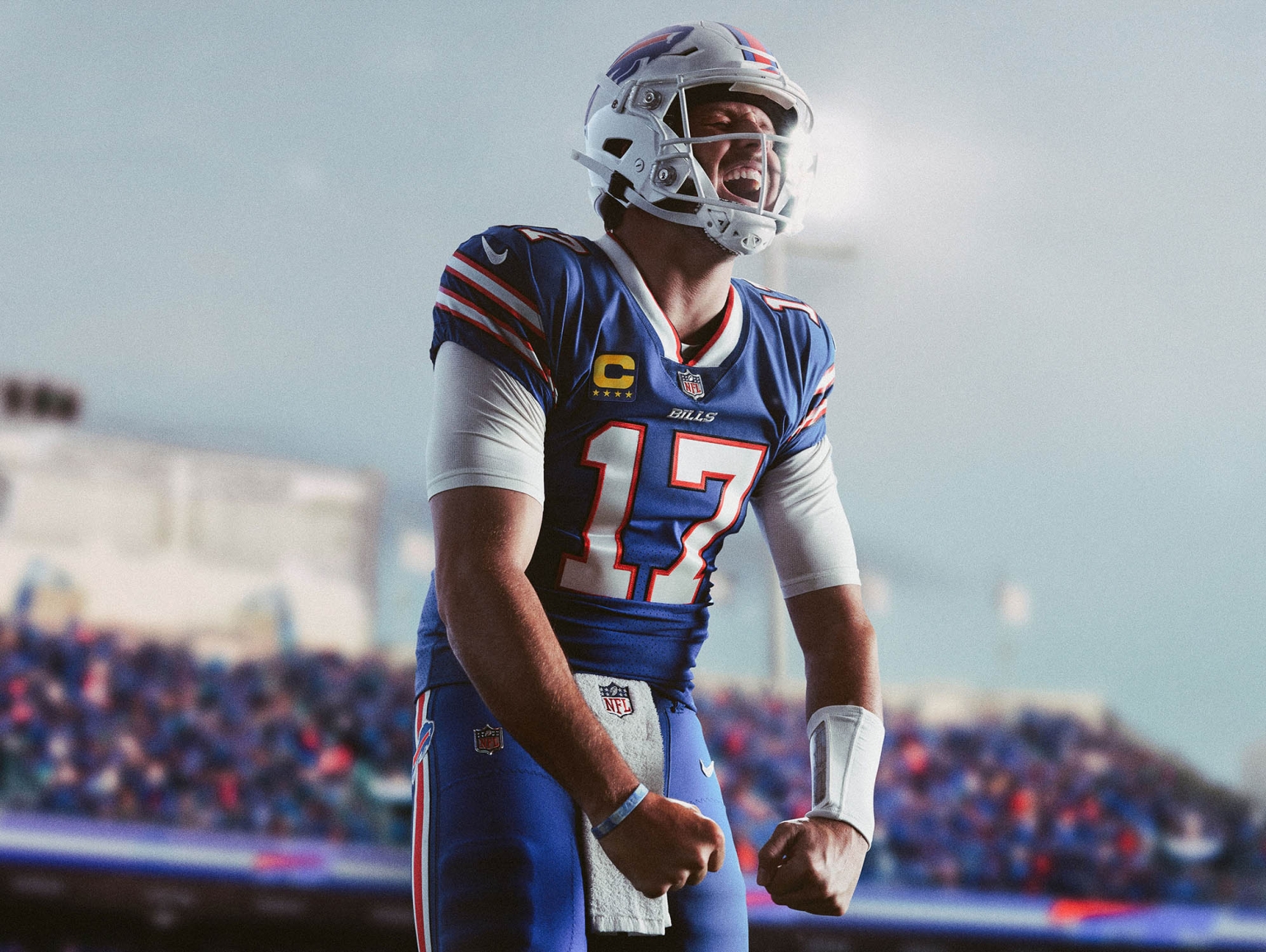 American football quarterback in a Bills uniform celebrates a play on the field with fans in the background. Excitement in sports.