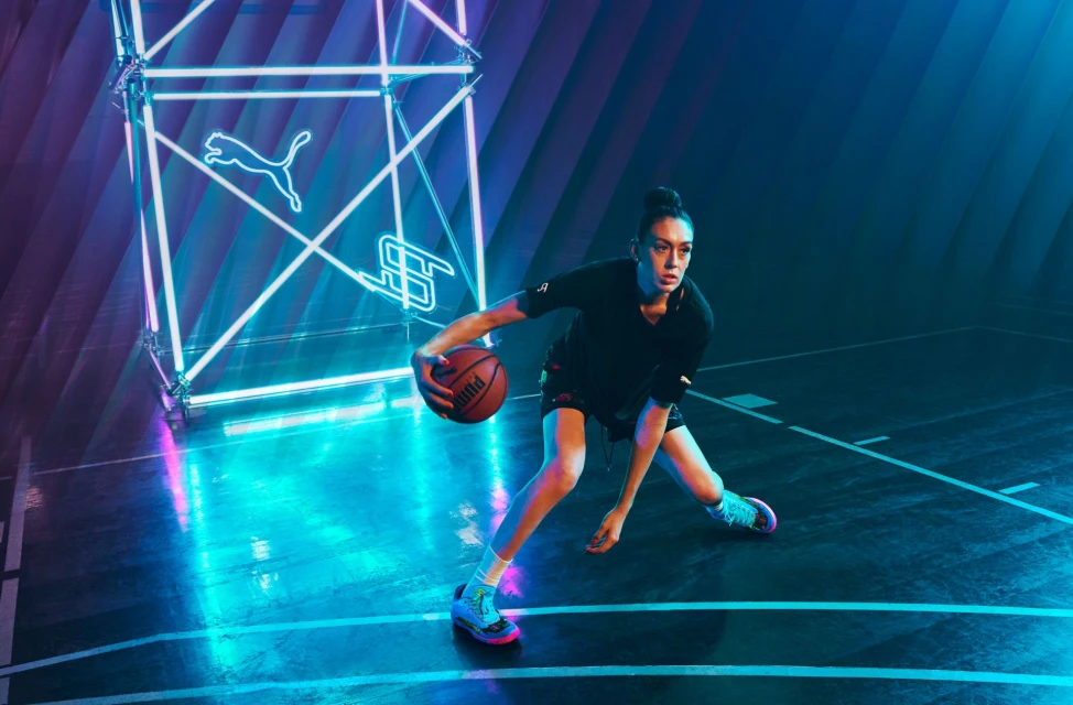 Female basketball player dribbling in neon-lit court. Focus on her athletic stance and the ball with geometric neon shapes behind her.