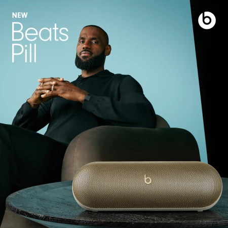 LeBron James poses in a photo studio with a Beats Pill speaker on a table, emphasizing a blend of celebrity and audio technology.