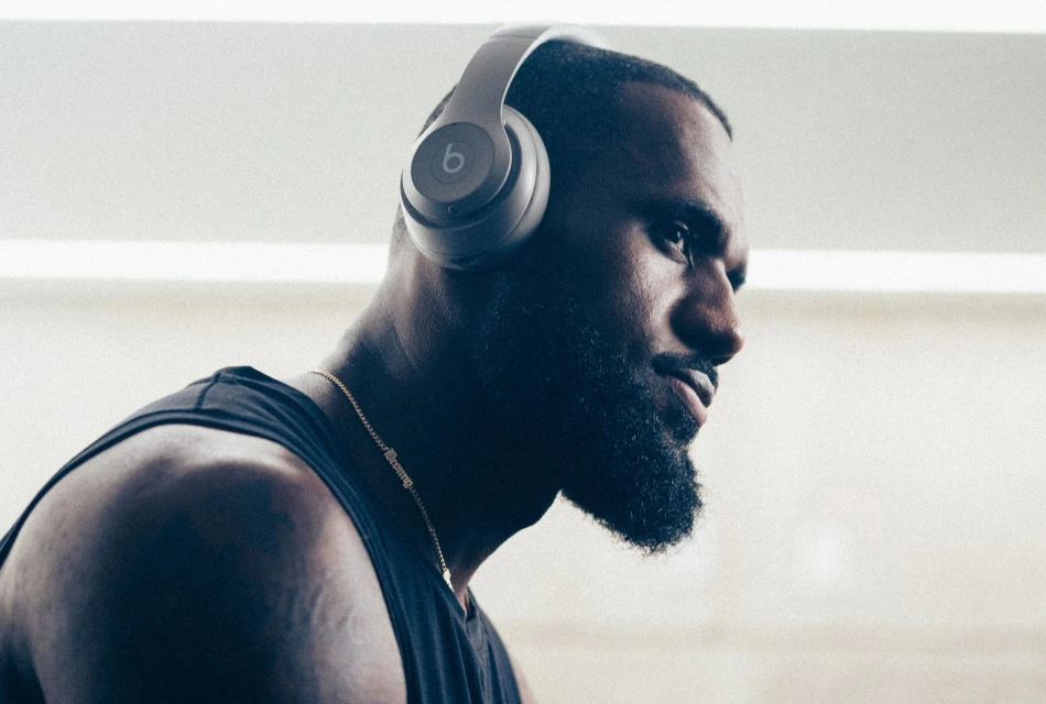 Close-up of an adult male wearing headphones and a tank top in an indoor setting, capturing his side profile and athletic physique.