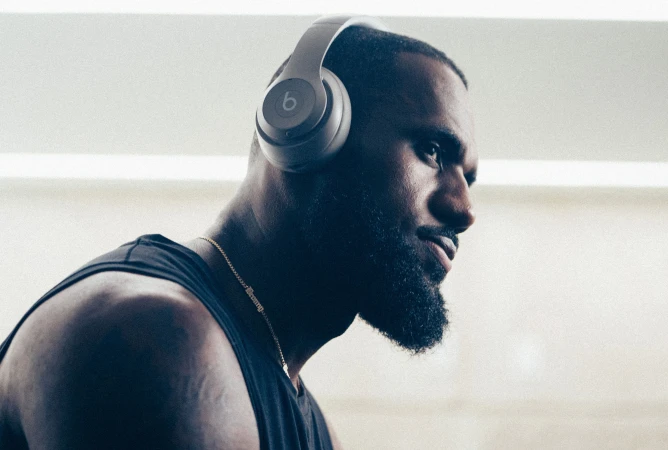Close-up of an adult male wearing headphones and a tank top in an indoor setting, capturing his side profile and athletic physique.