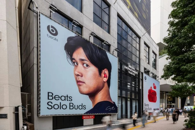 Billboard advertisement featuring an Asian male wearing an earbud for Beats Solo Buds, displayed on the side of a building in Tokyo.