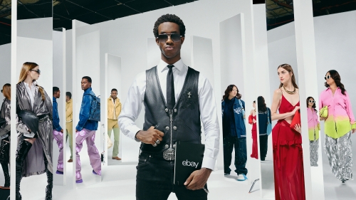 Fashion editorial shoot in a white photo studio featuring an African-American male model holding an eBay-branded notebook with other models.