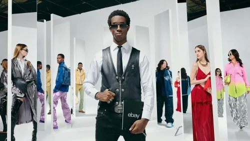 Fashion editorial shoot in a white photo studio featuring an African-American male model holding an eBay-branded notebook with other models.