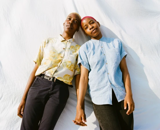 Two black people holding hands against a white fabric backdrop, photographed by Myles Loftin in New York.