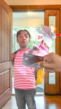 Boy stands at doorway looking surprised as a hand offers credit cards, creating a vibrant and engaging scene at a home entrance.
