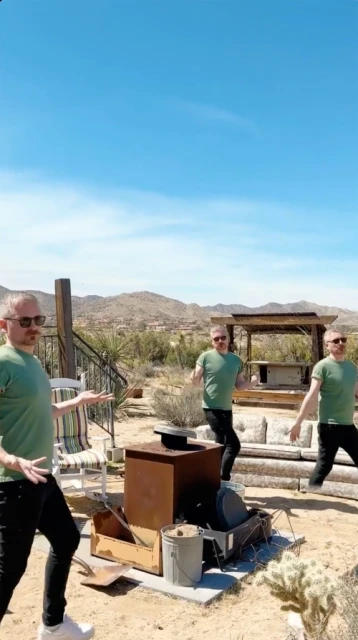 Three digitally cloned adult males in a desert backyard with arid landscape, wearing sunglasses, green shirts, and black jeans, dance.