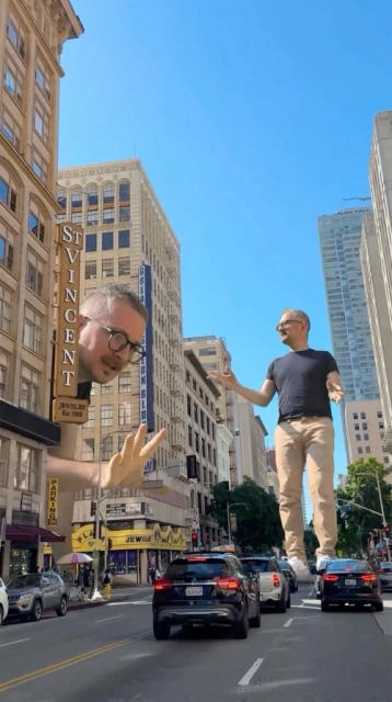 Surreal digital art of a giant man standing on cars in a city street, juxtaposed with a disembodied head and hand near buildings.