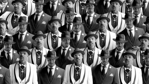 Crowd of serious men in pinstripe suits and hats, black-and-white photography showing a repetition of formal attire and vintage fashion.