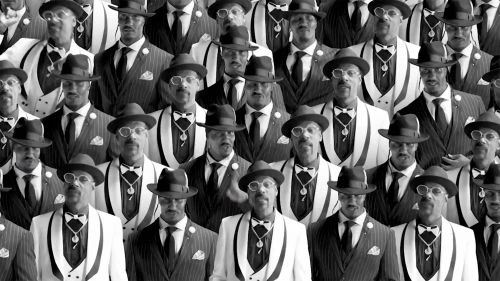 Crowd of serious men in pinstripe suits and hats, black-and-white photography showing a repetition of formal attire and vintage fashion.
