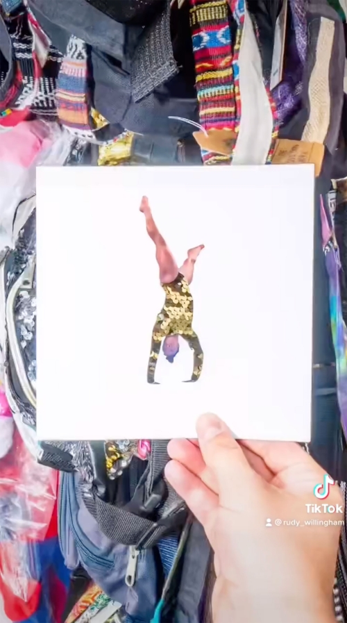 Close-up of an artful paper collage of a woman in a handstand, set against a backdrop of assorted clothing and accessories.