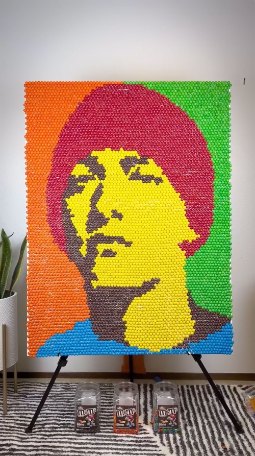 A colorful portrait mosaic art piece on an easel, created using jelly beans; the portrait displays a man's face on a vibrant background.