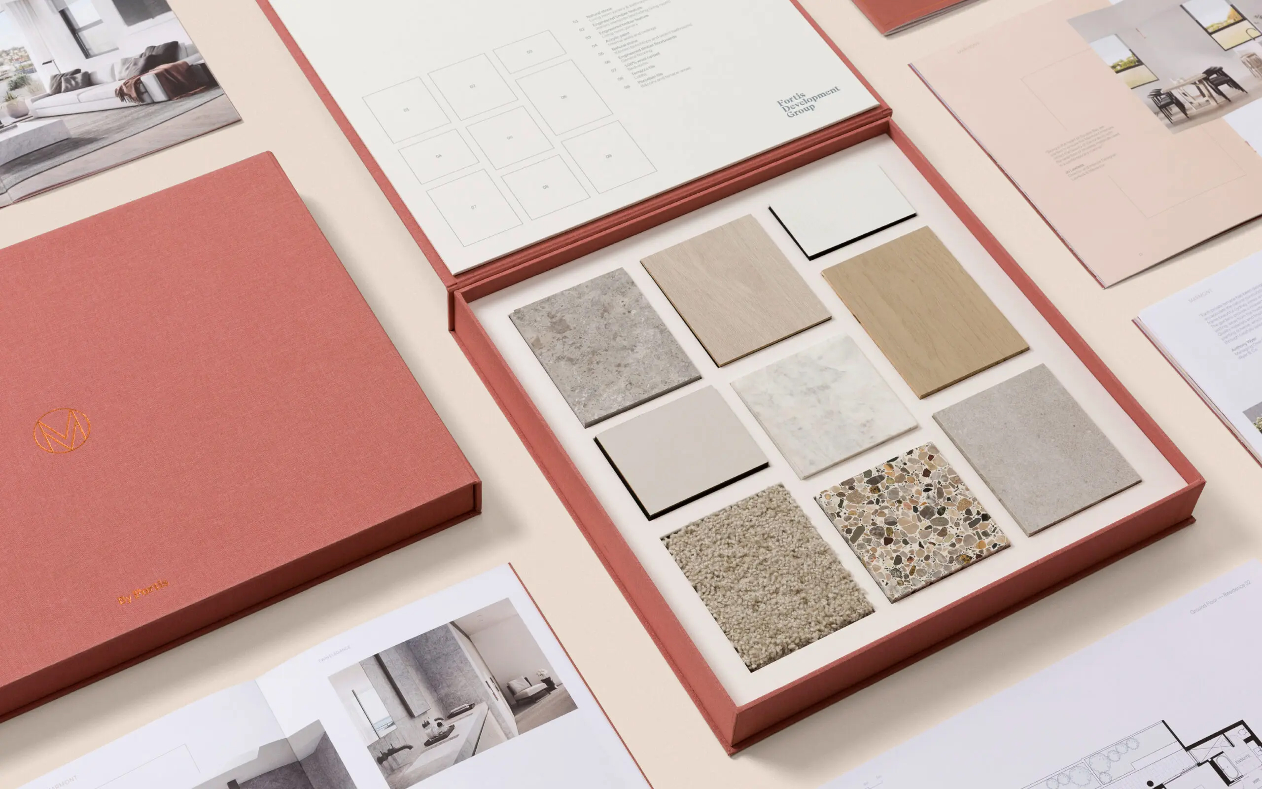 Interior design material sample box featuring various tiles and material swatches, accompanied by design brochures and layouts.