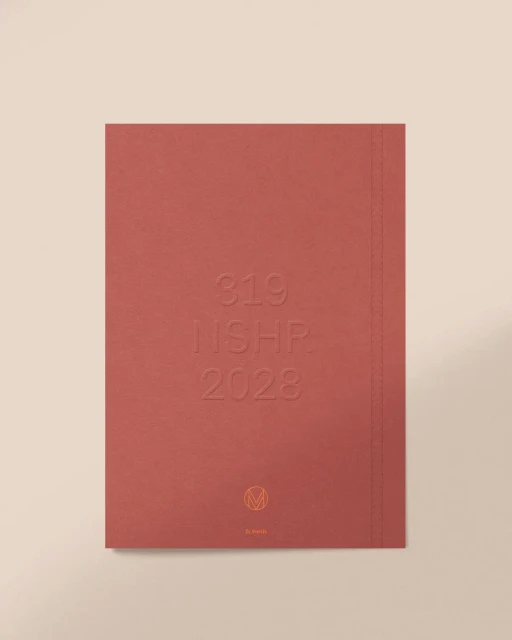 Textured salmon-colored notebook shows embossed numbers and letters under a soft light, casting a subtle shadow on a beige background.