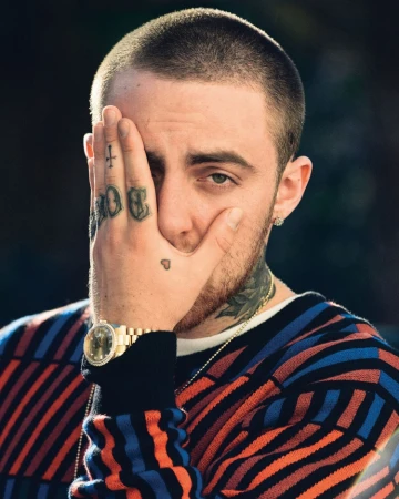 Close-up portrait of a man with hand tattoos covering part of his face, wearing a patterned sweater and a gold watch. 