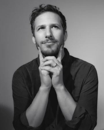 Portrait of Andy Samberg resting his chin on his hands with a pensive expression, captured by photographer Todd Cole.