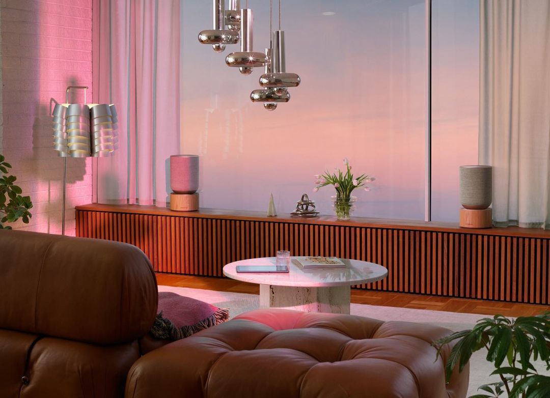 Cozy living room interior with brown leather furniture, modern lighting fixtures, wood paneling, and decorative objects in soft pastel colors.