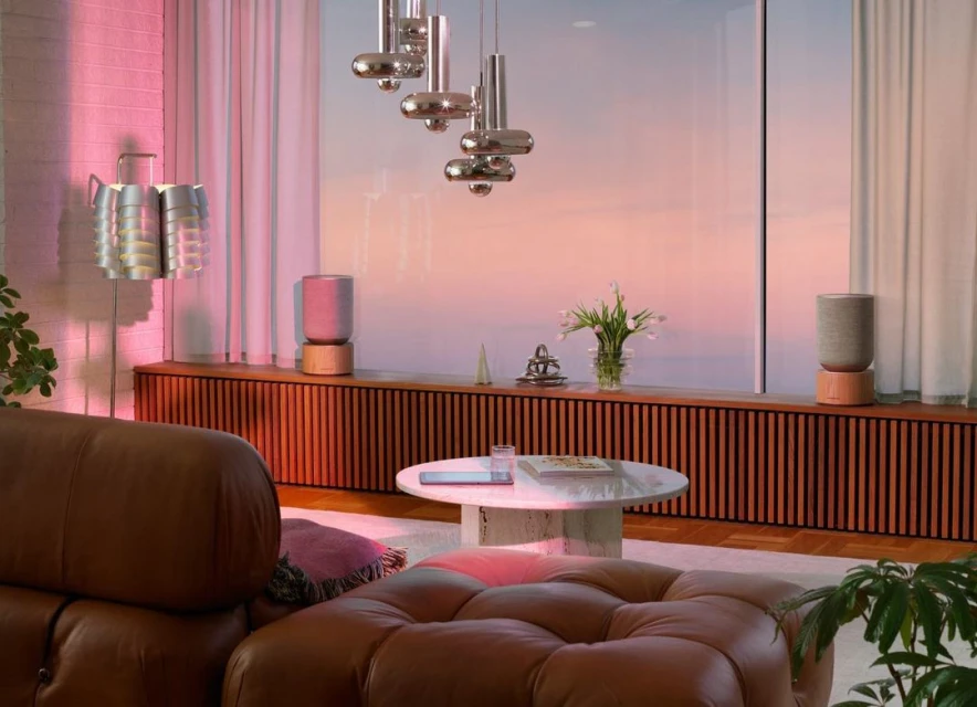 Cozy living room interior with brown leather furniture, modern lighting fixtures, wood paneling, and decorative objects in soft pastel colors.